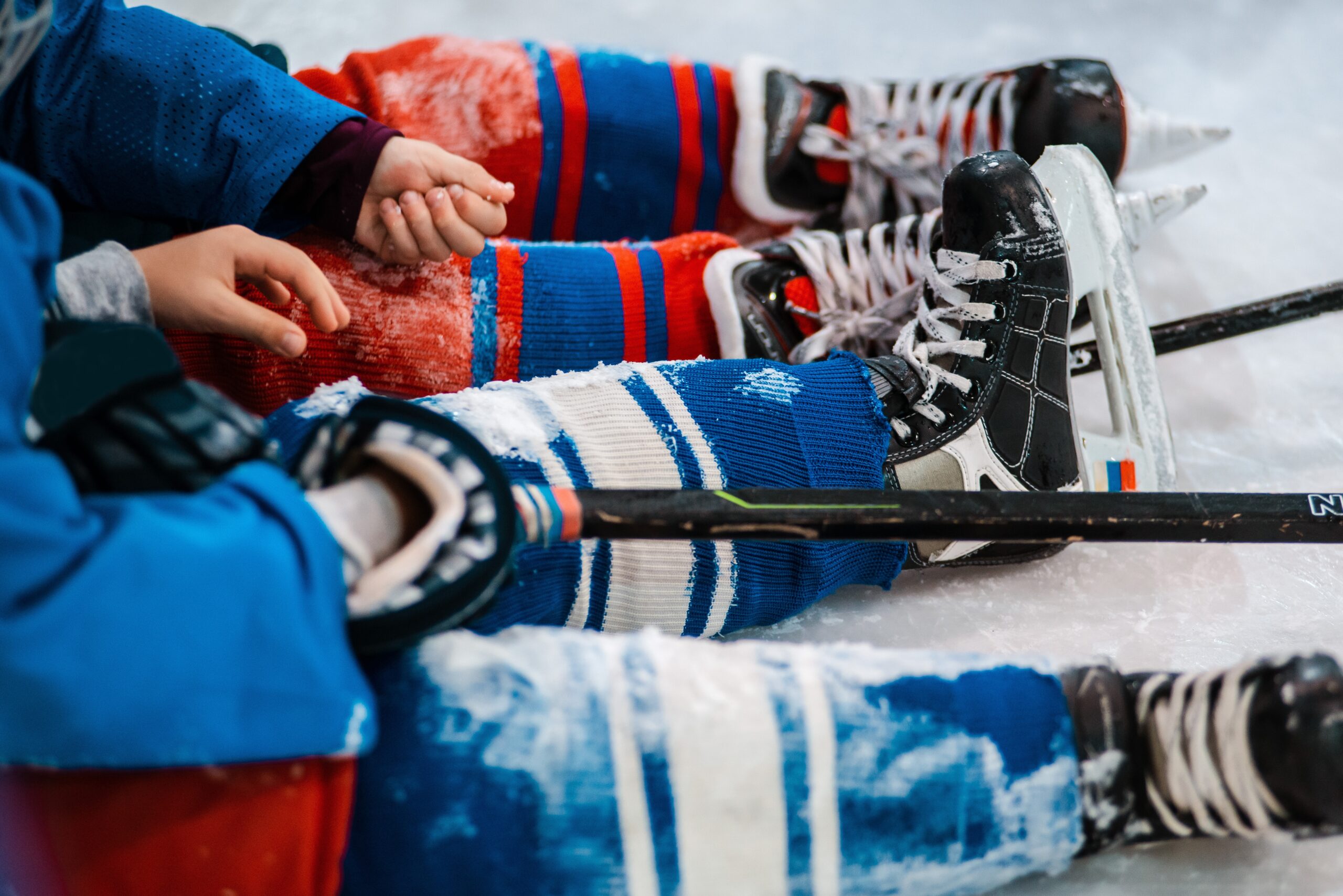 Six-year-old children hockey players sit on the ice in skates at the rink.